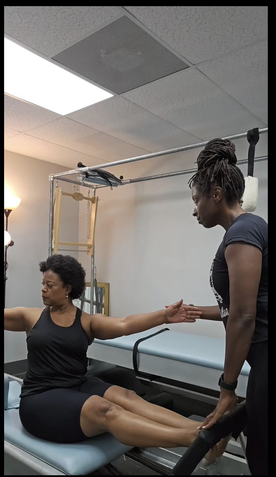 Laini Byfield guiding a client through arm extension on the Reformer